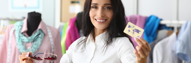 Smiling woman holding plastic credit card in clothing salon