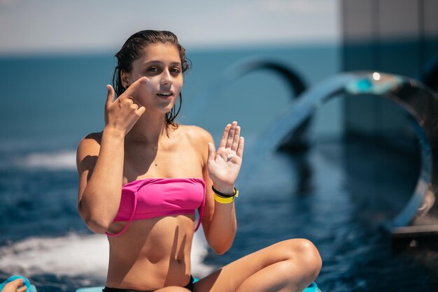 Smiling woman is applying sunscreen on her face