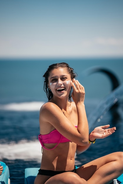 Smiling woman is applying sunscreen on her face