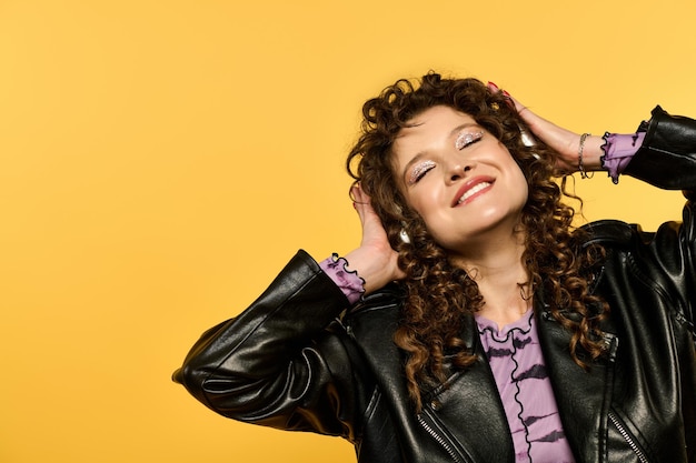 Smiling woman in leather jacket on yellow background