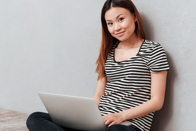 Smiling woman looking camera while working and holding laptop