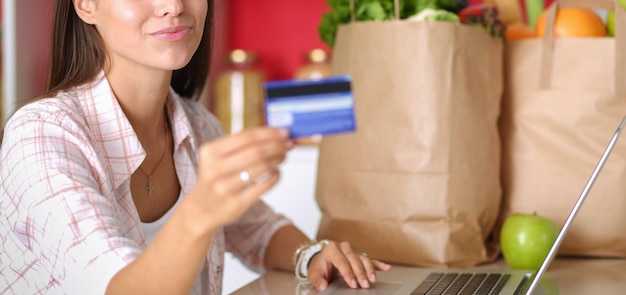 Smiling woman online shopping using tablet and credit card in kitchen Smiling woman