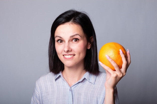 smiling woman in orange shirt holding grapefruit in her hands