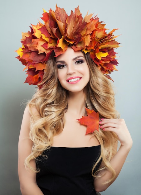 Smiling woman portrait Beautiful model with makeup healty curly hair and autumn leaves