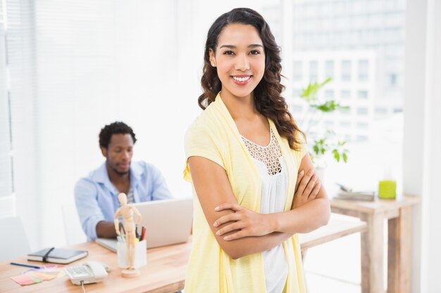 Smiling woman posing in front of her colleague with arms crossed 