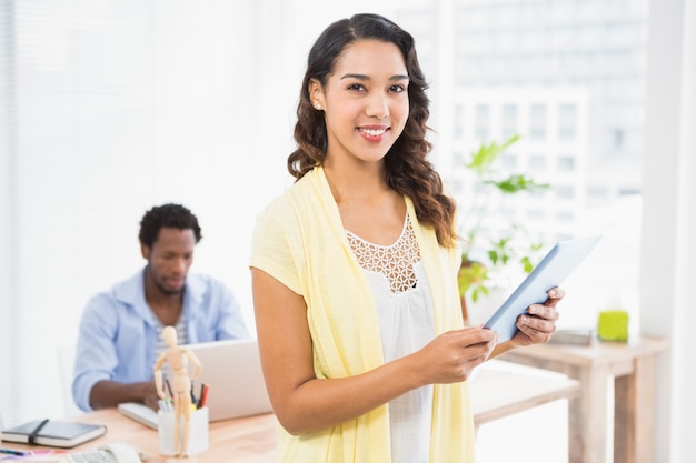 Smiling woman posing in front of her colleague with tablet computer