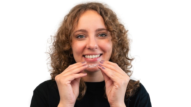 Smiling woman putting on her invisible silicone aligner for dental correction