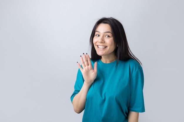 Smiling woman  raised her hand palm up and forward like waving.