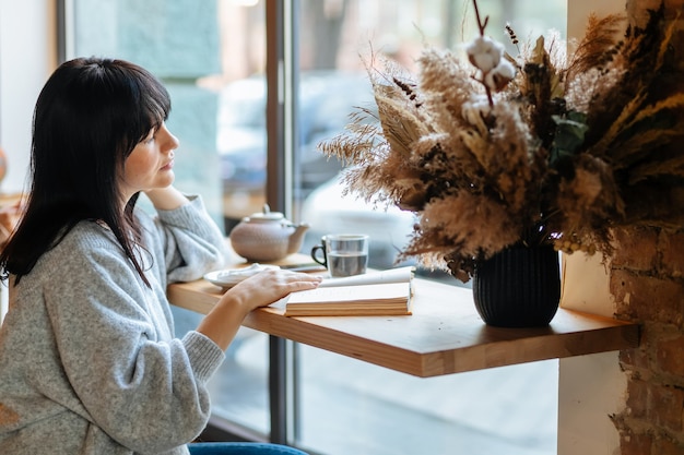 Smiling woman reading book at coffee shop