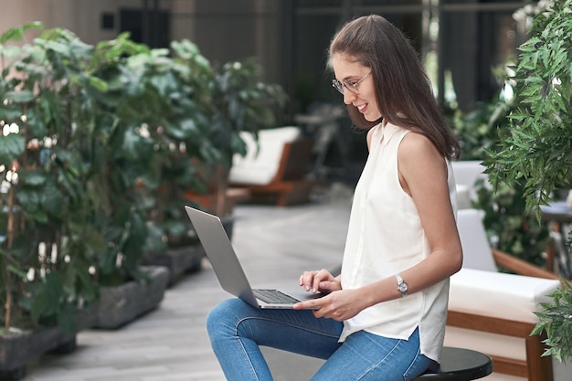 Smiling woman reading her email in an empty cafe hall