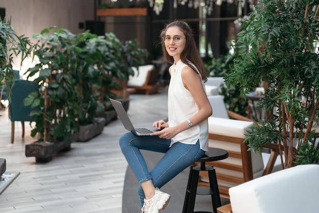 Smiling woman reading her email in an empty cafe hall