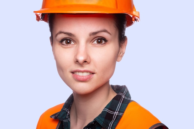 smiling woman in safety helmet orange vest blue background