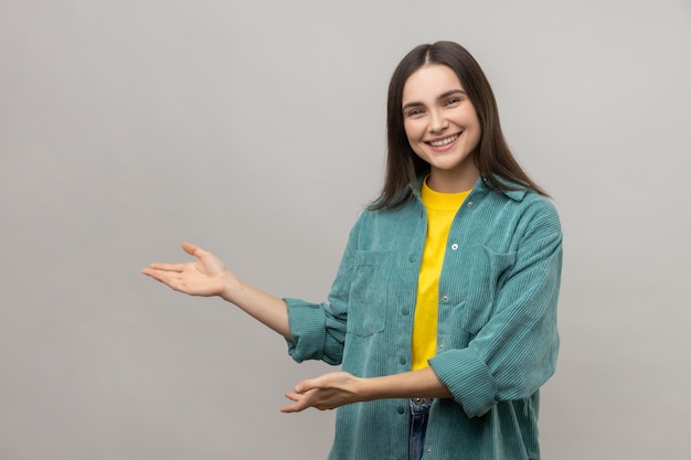 Smiling woman standing with wide raised arms and welcoming or sharing smth looking at camera