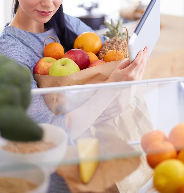 Smiling woman taking a fresh fruit out of the fridge healthy food concept