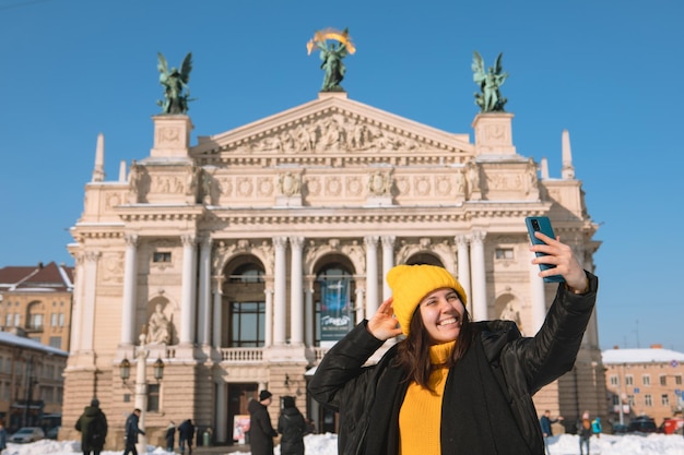 Smiling woman taking selfie in front of opera building