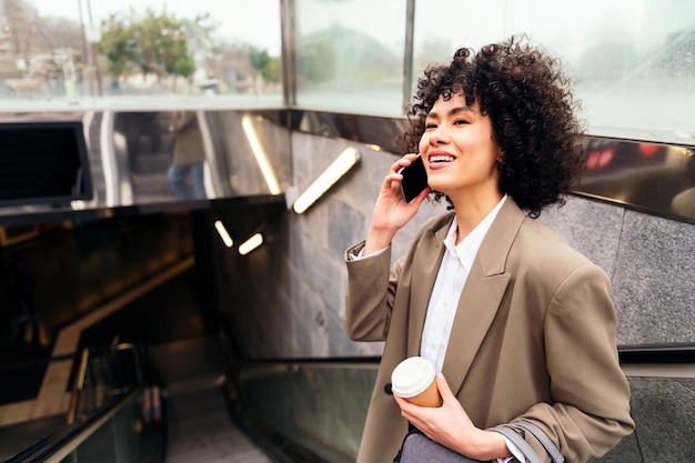 Smiling woman talking by phone on the escalator