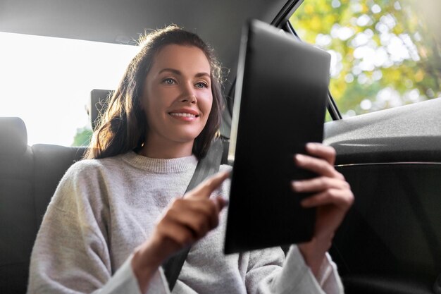 Photo smiling woman in taxi car using tablet pc computer