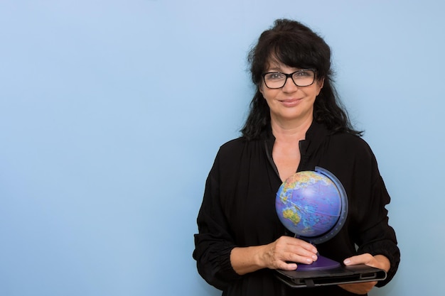 Smiling woman teacher with tablet and globe on blue background with copy space