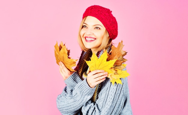 Smiling woman in warm clothes with yellow leaves autumn girl in red hat knitted sweater and scarf