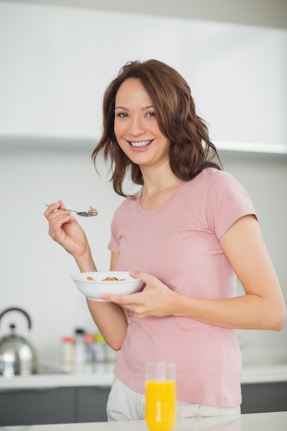 Smiling woman with a bowl of cereals in kitchen