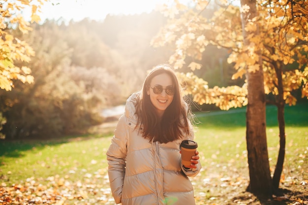 Smiling woman with coffee in the autumn park