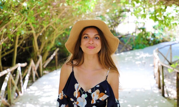 Smiling woman with hat and black dress outdoor