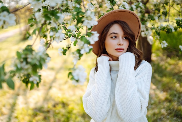 Smiling woman with hat posing in blooming spring park The concept of relax travel spring vacation