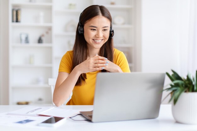 Smiling woman with headset using laptop at home office