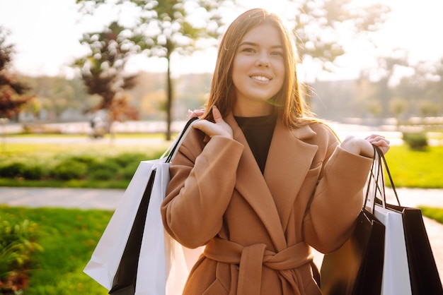 Smiling woman with shopping bags walking down the street Purchases black friday discounts