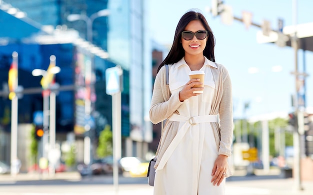 smiling woman with takeaway coffee cup in city