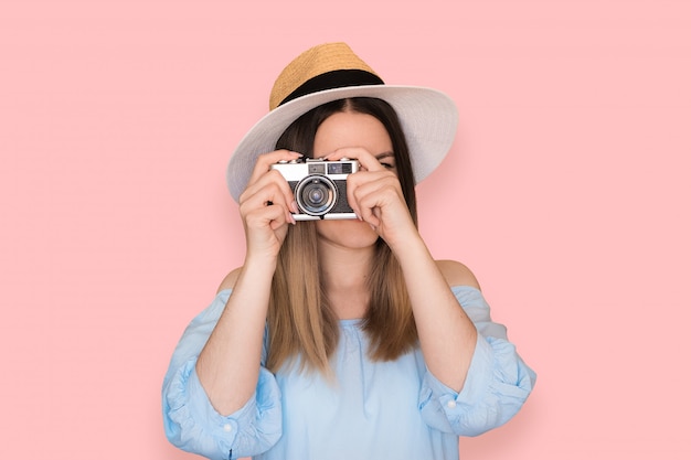 Smiling woman with vintage camera in blue dress on pink