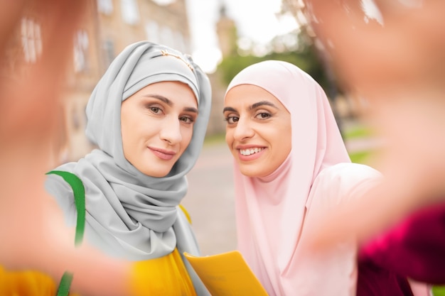 Smiling women. Dark-eyed young muslim women wearing hijabs smiling while making selfie