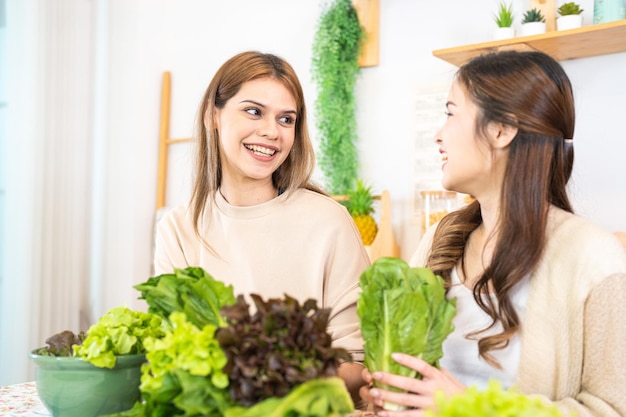 Smiling women preparing fresh healthy salad vegetables woman sitting at pantry in a beautiful interior kitchen The clean diet food from local products and ingredients Market fresh