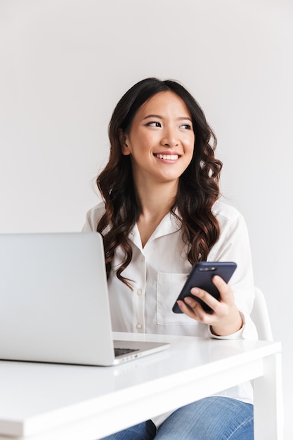 Smiling young asian businesswoman holding mobile phone