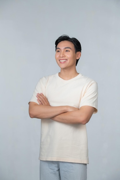 Smiling young Asian man with arms crossed on a white background