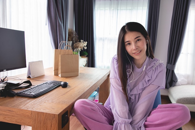 Photo smiling young asian woman listening music in living room.