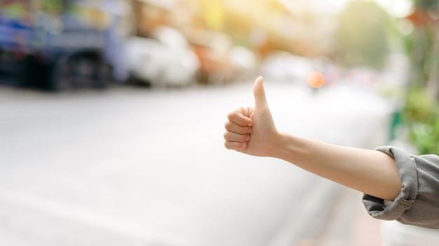 Smiling young Asian woman traveler hitchhiking on a road in the city Life is a journey concept