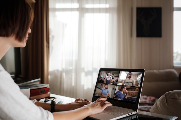 Smiling young asian woman video calling on laptop