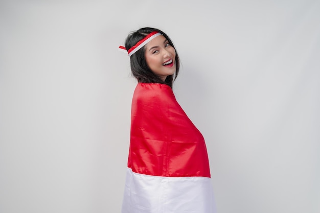 Photo smiling young asian woman with indonesian flag draped over her shoulders