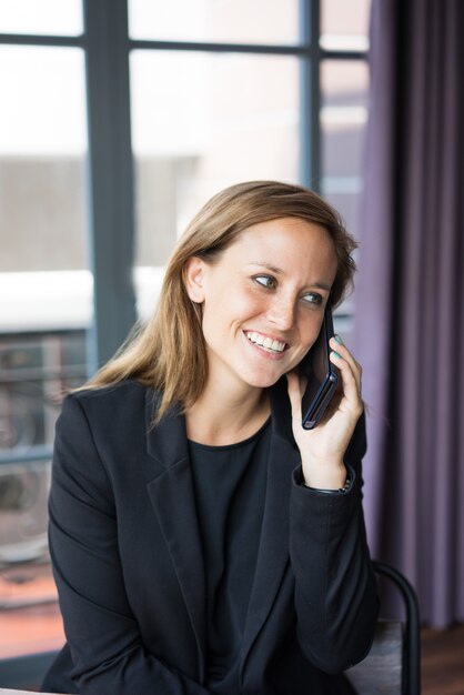 smiling young beautiful brown-haired woman looking away, talking on smartphone 