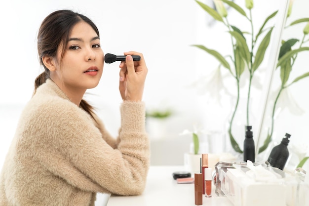 Smiling of young beautiful pretty asian woman clean fresh healthy white skinasian girl holding makeup brushes and make up on face with cosmetics set at homefacial beauty