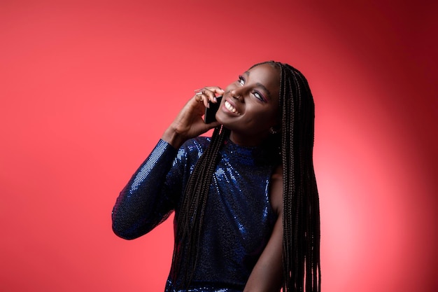 Smiling young black female in sequin dress talking on cellphone