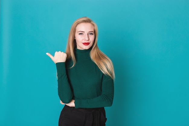 Smiling young blonde longhair woman poiting her finger aside