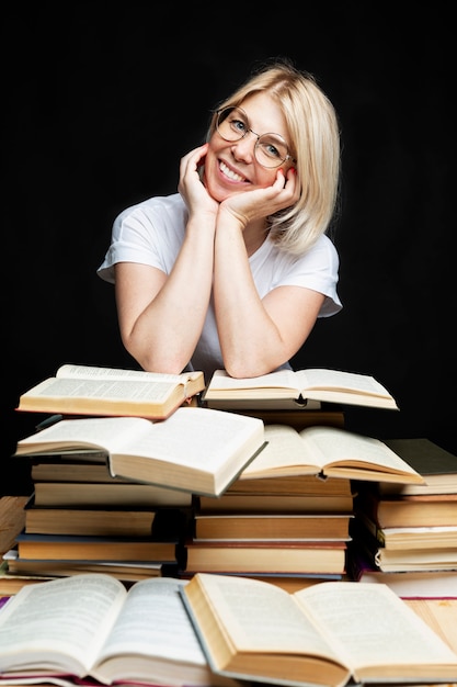 Smiling young blonde woman with a pile of books. Education, knowledge and hobbies.