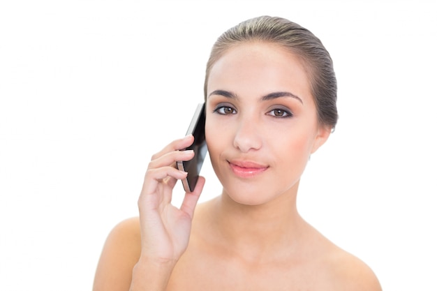 Smiling young brunette woman holding a mobile phone