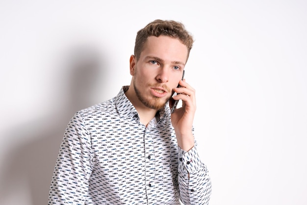 Smiling young business man in a light shirt posing on a light background