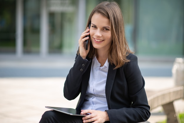 Smiling young business woman using her mobile cell phone