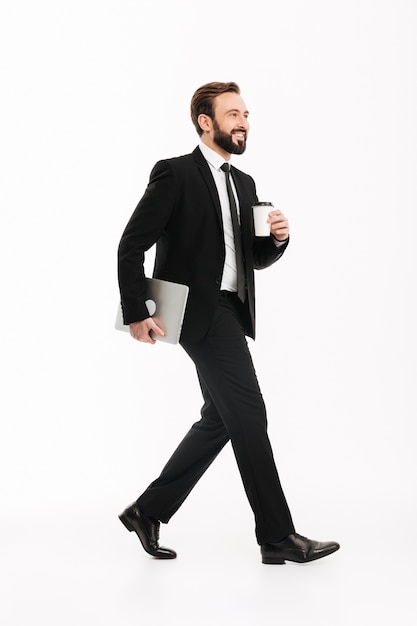 Smiling young businessman holding laptop computer.