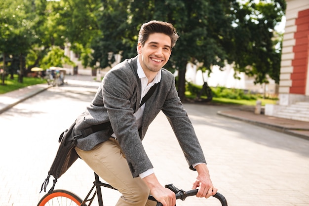 Smiling young businessman riding a bicycle