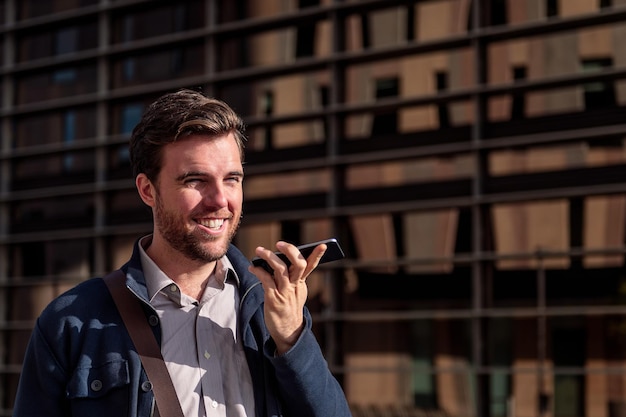 Smiling young businessman sending a voice message